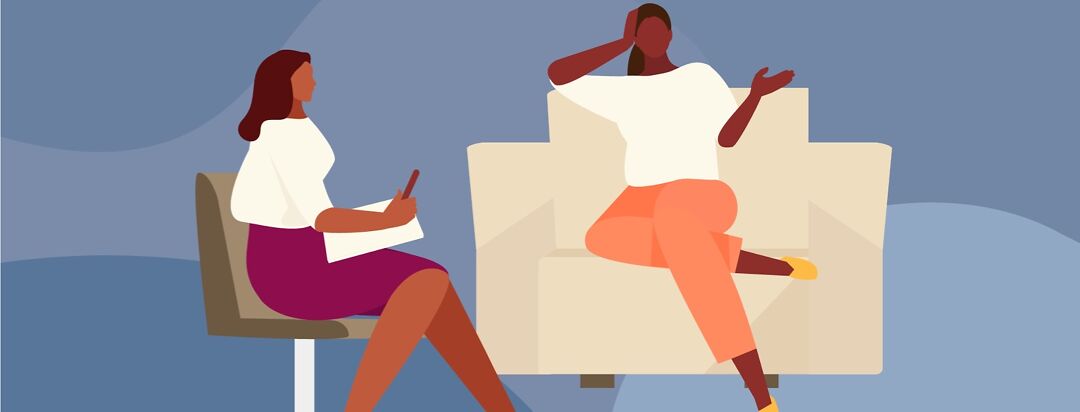 A woman sits on a sofa and speaks to her therapist in person